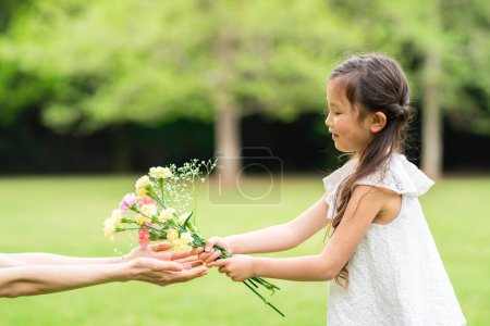 Photo for A child giving to mother  flowers outdoors - Royalty Free Image