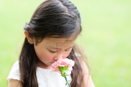 Téléchargez les photos : Fille sentant l'oeillet rose - en image libre de droit