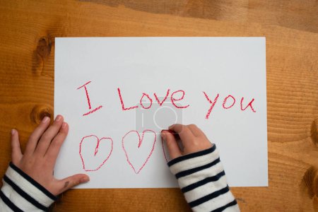 Foto de Niño que escribe Te amo en papel - Imagen libre de derechos