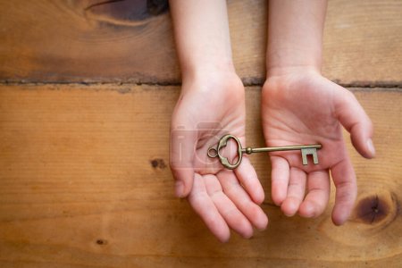 Téléchargez les photos : Les mains de l'enfant tenant une clé - en image libre de droit