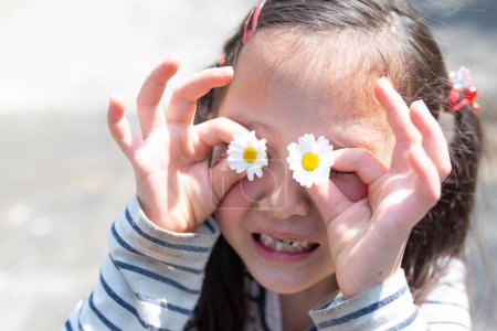 Téléchargez les photos : Fille jouer avec des fleurs sur les yeux - en image libre de droit