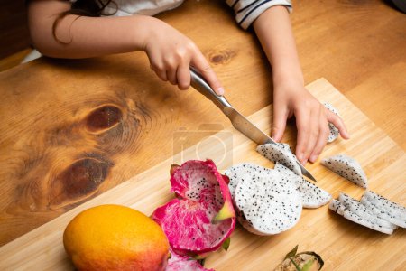 Photo for Child cutting dragon fruit - Royalty Free Image
