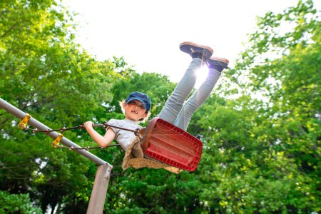 Téléchargez les photos : Mignonne petite fille asiatique sur swing sur aire de jeux dans le parc - en image libre de droit