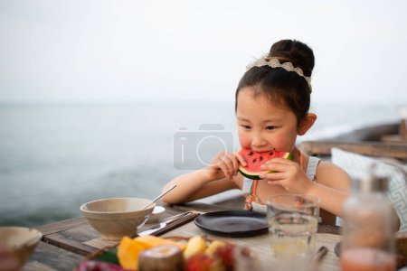 Téléchargez les photos : Fille manger pastèque à table - en image libre de droit