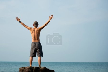 Téléchargez les photos : Un homme étendant ses mains dans la mer - en image libre de droit