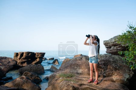 Girl look with binoculars in the sea