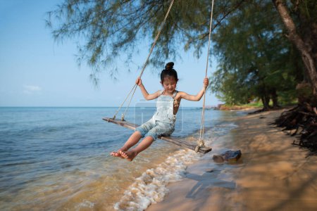 Téléchargez les photos : Fille jouer sur swing sur la plage - en image libre de droit