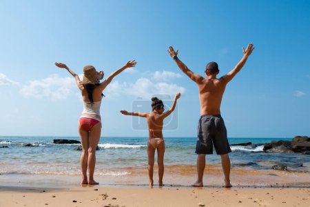 Téléchargez les photos : Jeune famille avec les mains en l'air sur la plage - en image libre de droit