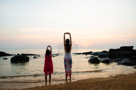 Téléchargez les photos : Mère et fille jouant à la plage du coucher du soleil - en image libre de droit