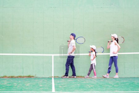 Photo for Father and mother and daughter on tennis court - Royalty Free Image