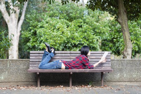 Photo for Asian girl reading a book in the park - Royalty Free Image