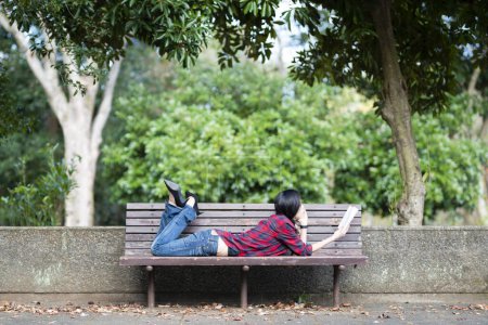 Téléchargez les photos : Asiatique fille lecture un livre dans l 'parc - en image libre de droit