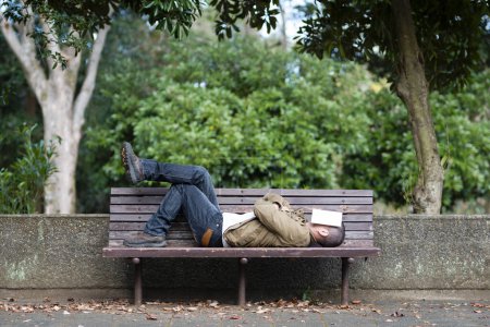 Photo for Man take a nap on a bench in the park - Royalty Free Image
