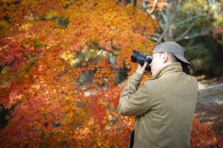 Photo for Man photographing autumn leaves - Royalty Free Image