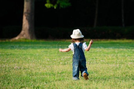 Téléchargez les photos : Petite fille jouant sur la pelouse - en image libre de droit