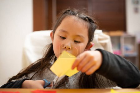 Téléchargez les photos : Fille jouer avec origami à la table - en image libre de droit