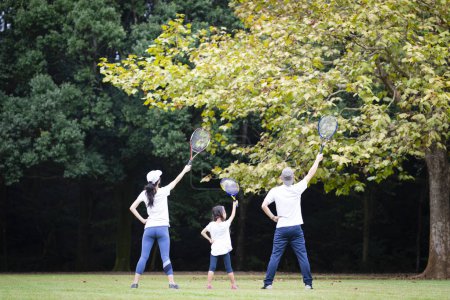 Téléchargez les photos : Famille avec raquette de tennis sur prairie - en image libre de droit