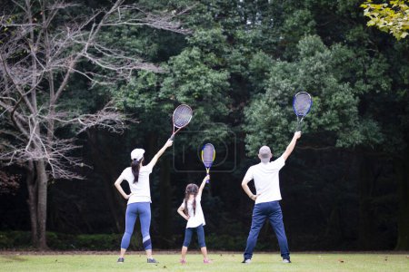 Téléchargez les photos : Famille avec raquette de tennis sur prairie - en image libre de droit
