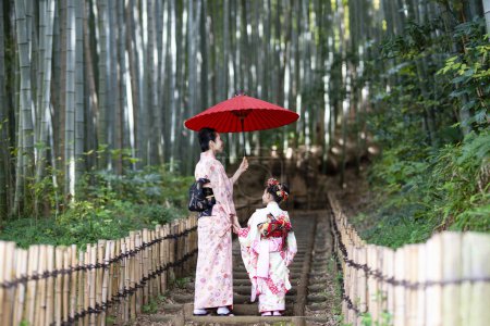 Foto de Joven asiático madre con hija en tradicional japonés vestidos en bambú bosque - Imagen libre de derechos