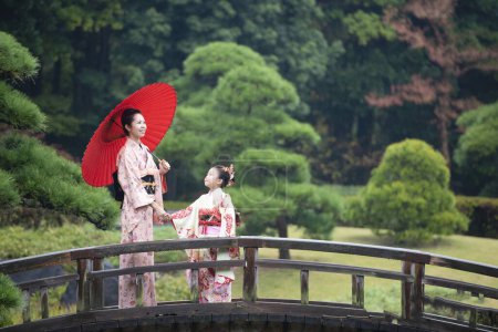 Téléchargez les photos : Jeune asiatique mère avec fille dans traditionnel japonais robes sur pont - en image libre de droit