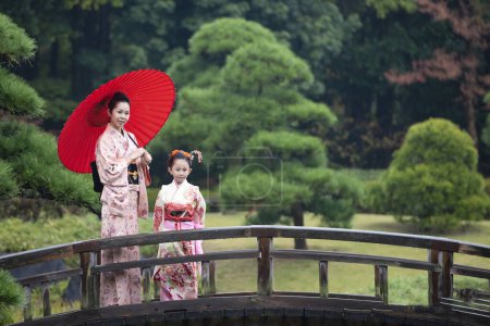 Téléchargez les photos : Jeune asiatique mère avec fille dans traditionnel japonais robes sur pont - en image libre de droit