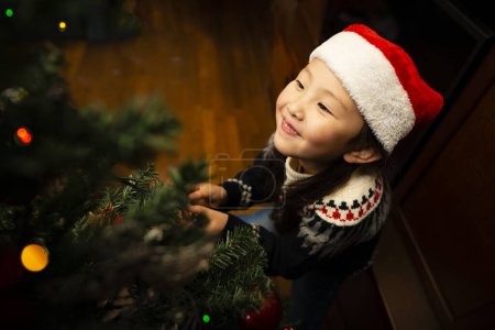 Photo for Girl to decorate the Christmas tree - Royalty Free Image