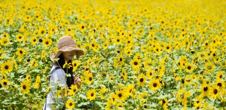 Photo for Woman relaxing in a sunflower field - Royalty Free Image
