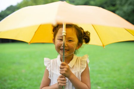 Téléchargez les photos : Fille utilise un parapluie sur la pelouse - en image libre de droit