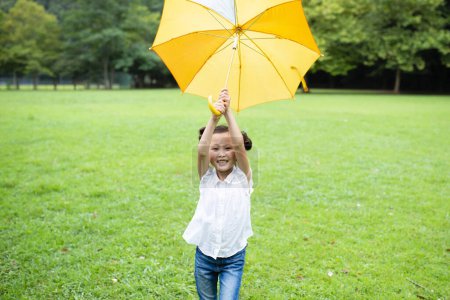 Photo for Girl uses an umbrella on lawn - Royalty Free Image