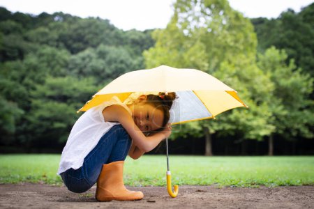 Photo for Girl uses an umbrella on lawn - Royalty Free Image