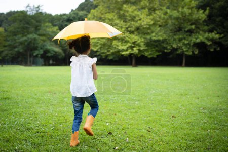 Foto de Chica utiliza un paraguas en el césped - Imagen libre de derechos
