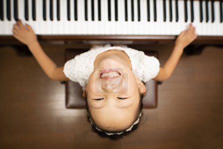 Photo for Asian girl playing piano at home, top view - Royalty Free Image
