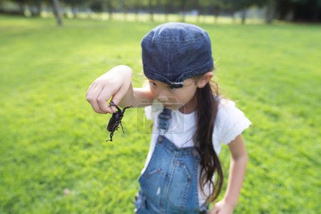 Foto de Niña con un escarabajo en el césped - Imagen libre de derechos