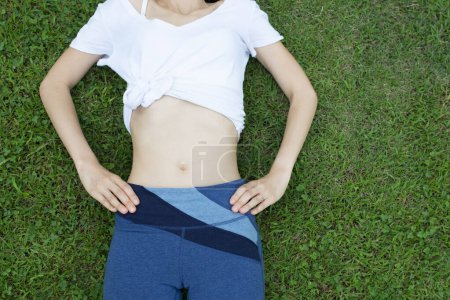 Téléchargez les photos : L'estomac de la belle femme sur la pelouse verte - en image libre de droit