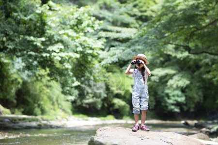 Photo for Child using binoculars by the river - Royalty Free Image