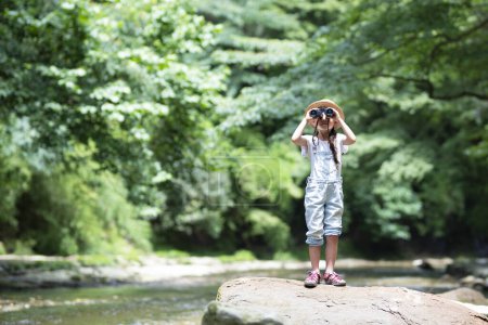 Foto de Niño usando prismáticos junto al río - Imagen libre de derechos