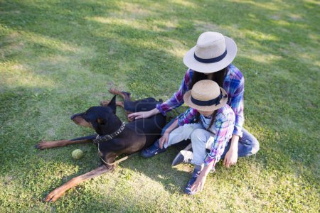 Téléchargez les photos : Parent et chien relaxant sur la pelouse - en image libre de droit
