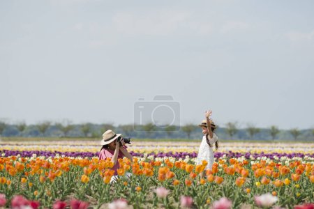 Téléchargez les photos : Belle asiatique mère prise photo de fille dans l 'fleur champ - en image libre de droit
