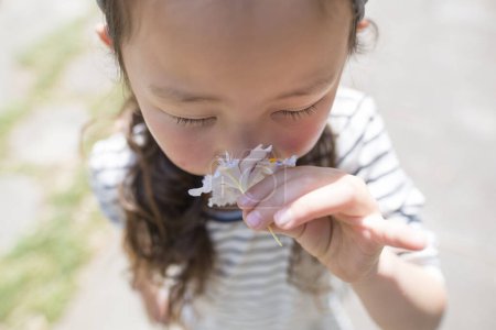 Photo for Little girl sniffing the scent of flower - Royalty Free Image
