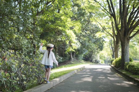 Téléchargez les photos : Petite fille marche trottoir dans le parc - en image libre de droit