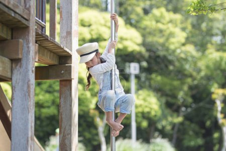 Téléchargez les photos : Mignonne petite fille asiatique jouer sur aire de jeux dans le parc - en image libre de droit