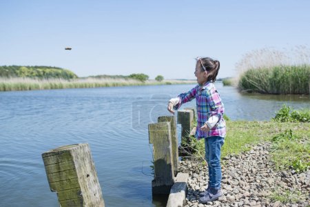 Photo for Little girl who throws a stone in a pond - Royalty Free Image