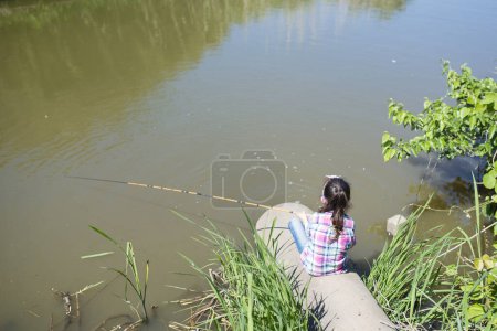 Téléchargez les photos : Petite fille pêche sur le lac ou le rivage de la rivière - en image libre de droit
