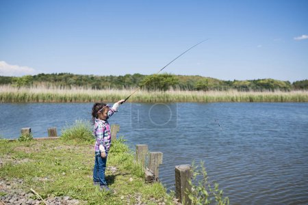 Photo for Little girl fishing on lake or river shore - Royalty Free Image