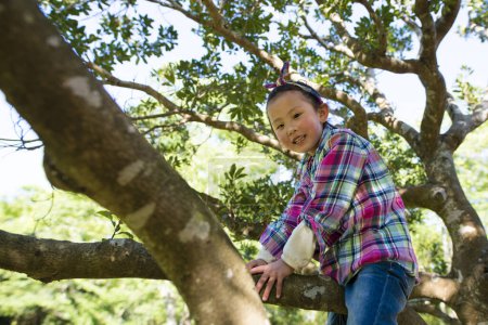Téléchargez les photos : Petite fille grimpant à un arbre - en image libre de droit