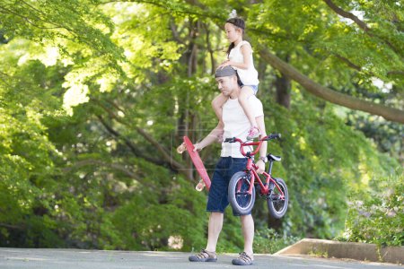 Téléchargez les photos : Père et fille marchant dans un parc ensoleillé - en image libre de droit