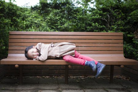 Photo for Little girl to relax on the park bench - Royalty Free Image