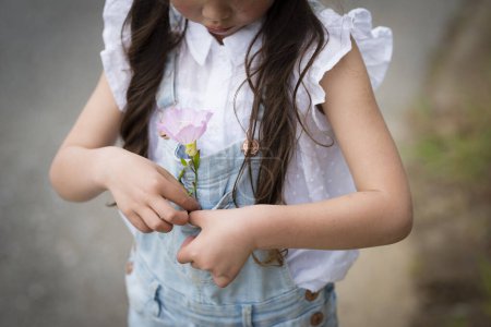 Photo for Girl in overalls pocket put a flower - Royalty Free Image