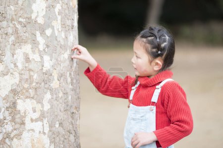 Photo for Little girl touching tree outdoors - Royalty Free Image