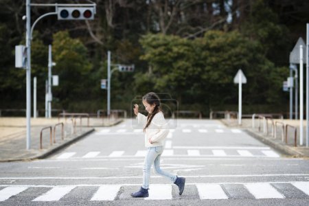 Téléchargez les photos : Petite fille traversant un passage piétonnier - en image libre de droit